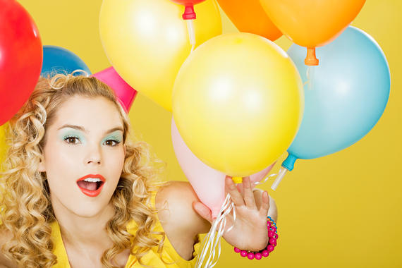 Young blonde woman with balloons against yellow background